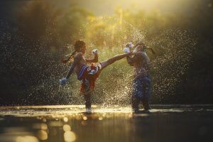 Zwei Muay Thai Kämpfer mit den Füßen im Wasser die kämpfen.